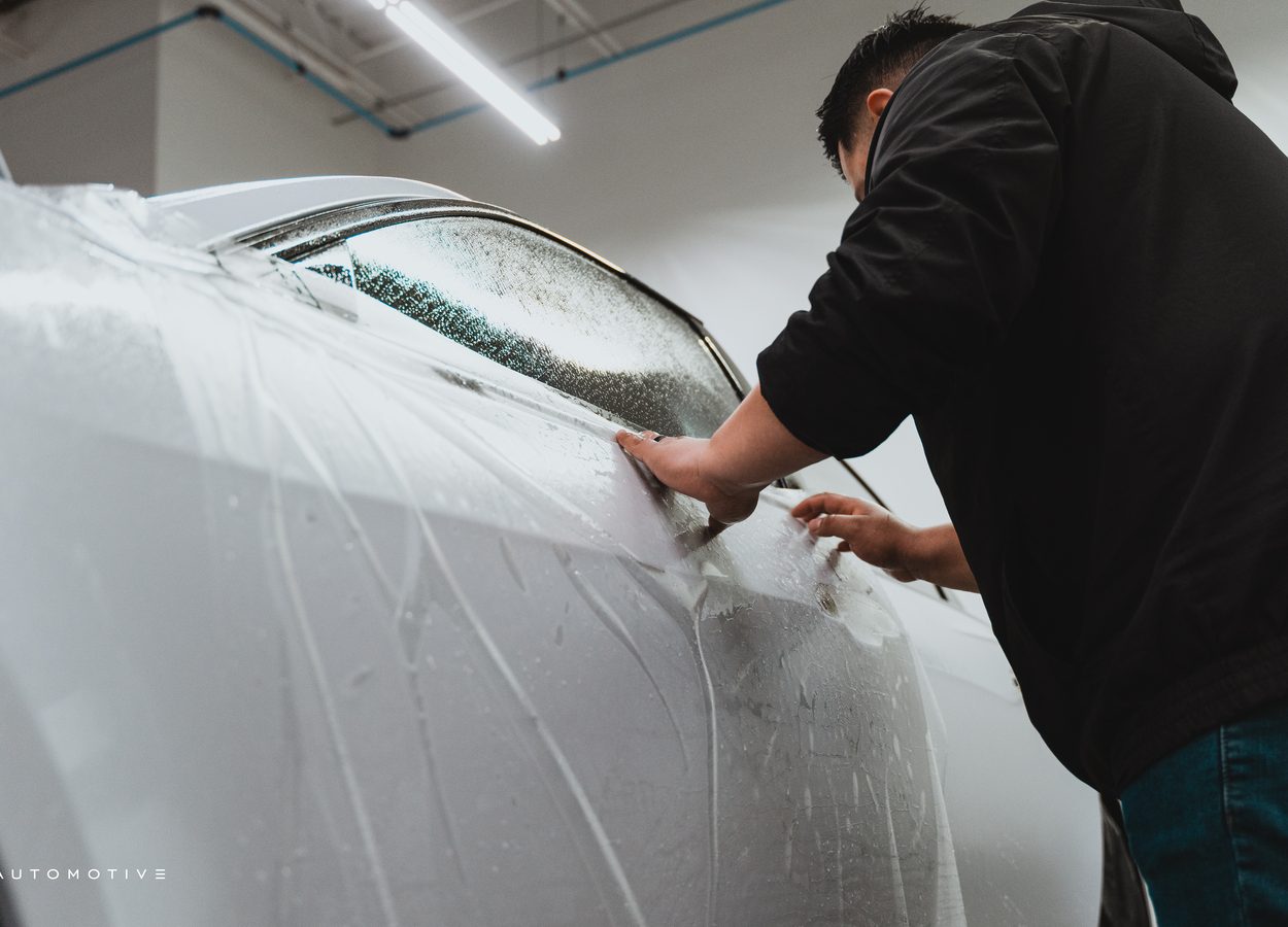 tech applying paint protection to door of luxury car